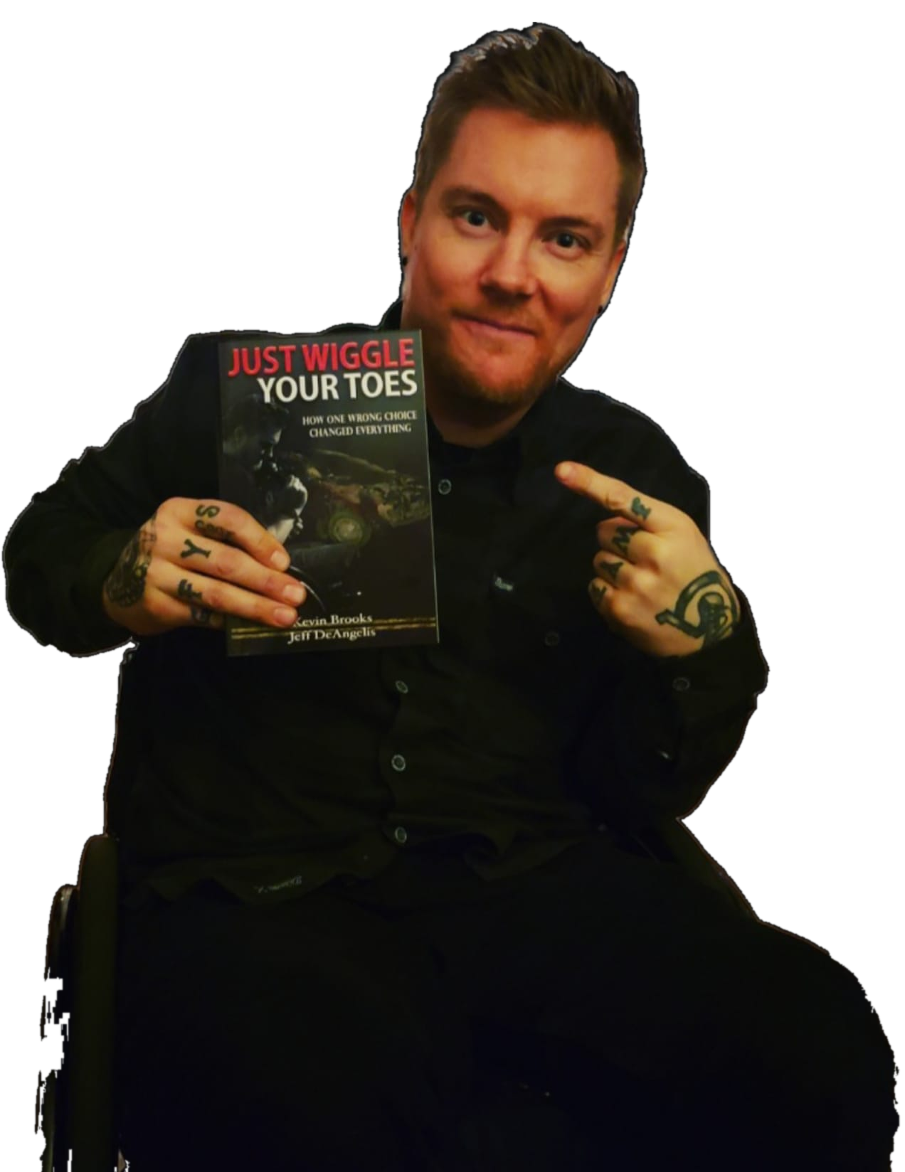 Kevin in his wheelchair, holding up his book Just Wiggle Your Toes and pointing at it